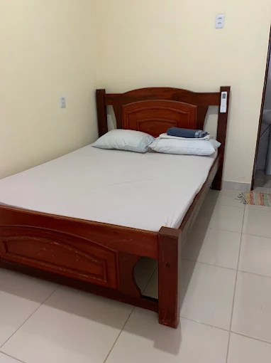 Quarto com cama de madeira e roupa de cama branca